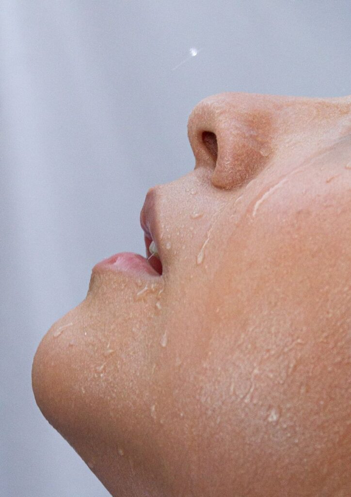 Macro photo of a person's face with water droplets highlighting skin texture.